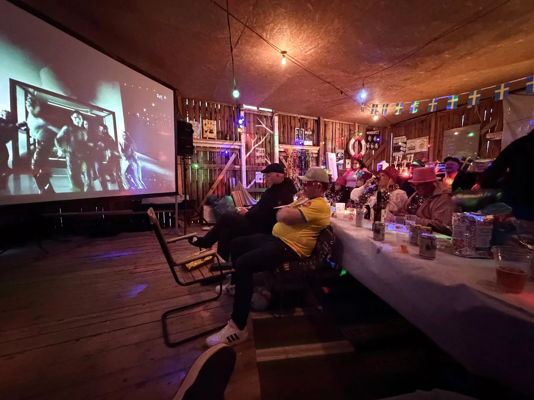 Publik vid långbord framför storbild på en community-kväll.