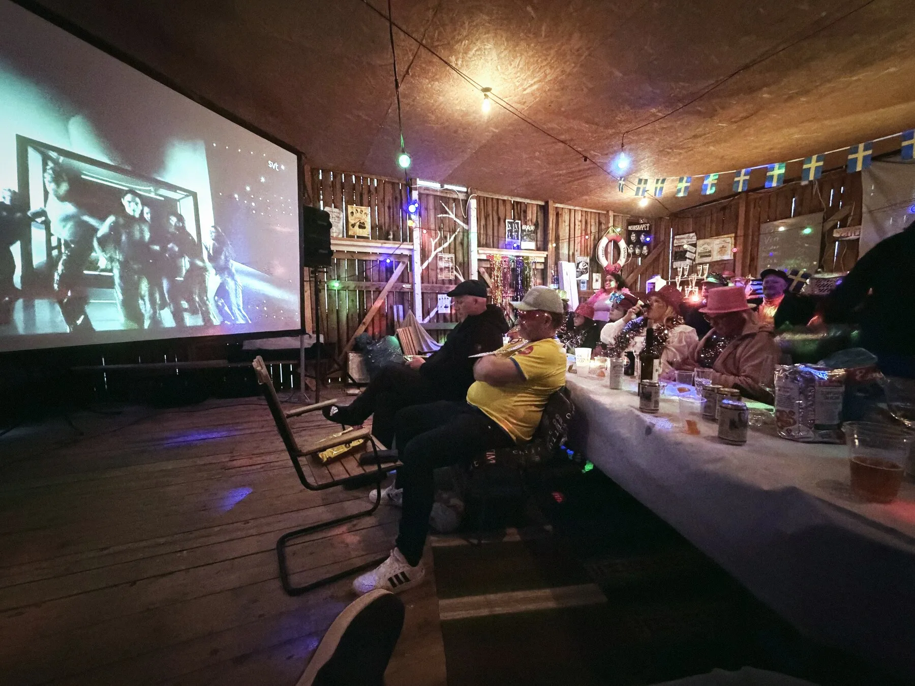 Publik vid långbord framför storbild på en community-kväll.